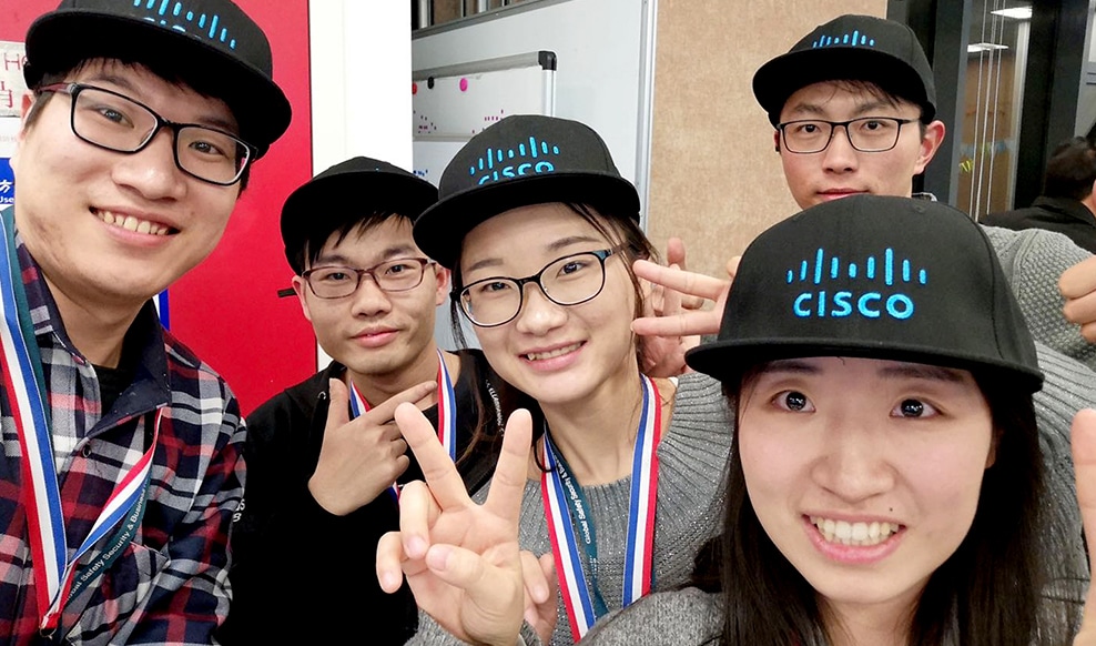 Selfie of five people smiling and wearing Cisco ballcaps.