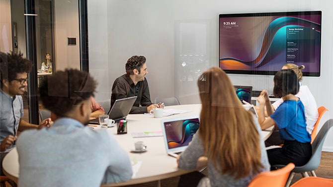 Équipe travaillant de manière hybride en réunion dans une salle de collaboration optimisée par Cisco