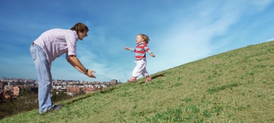 Small child running down a hill to father