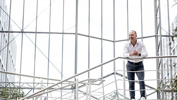 Michael of Fond Finanz leaning over balcony in office building