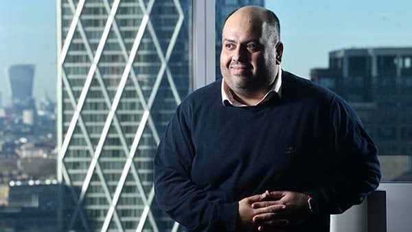 Umar Ahmed of Deutsche Bank standing in office with city view