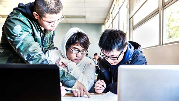 Three men working together with a laptop