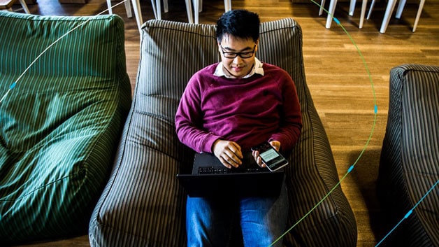 student with multiple devices sitting in chair