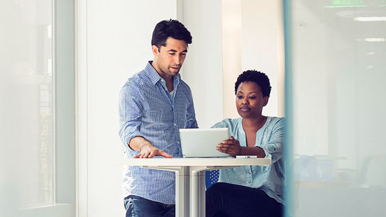 Two people in office environment viewing small wireless device